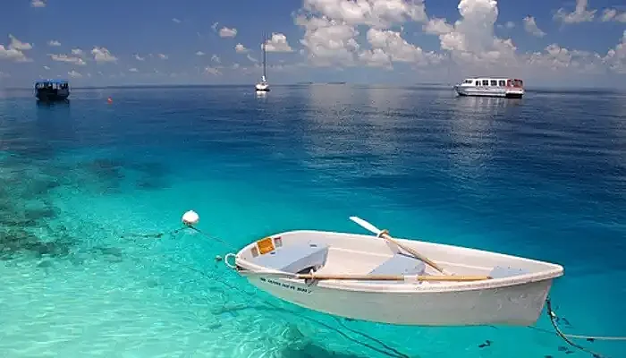 A boat parked in the turquoise waters near the Fihalhohi Island 
